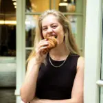 Foto van Lisa Oudijn die een hap neemt van een croissantje.