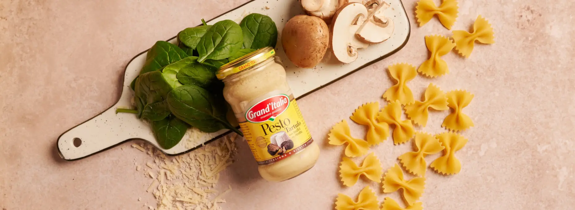 Een pot Grand'Italia Pesto Tartufo met verse spinazie, champignons en farfalle pasta.