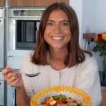 Een foto van Joosje; spontane jonge dame met bruin haar en een wit shirtje. Ze glimlacht en houdt een bord met Grand'Italia pasta vast. 