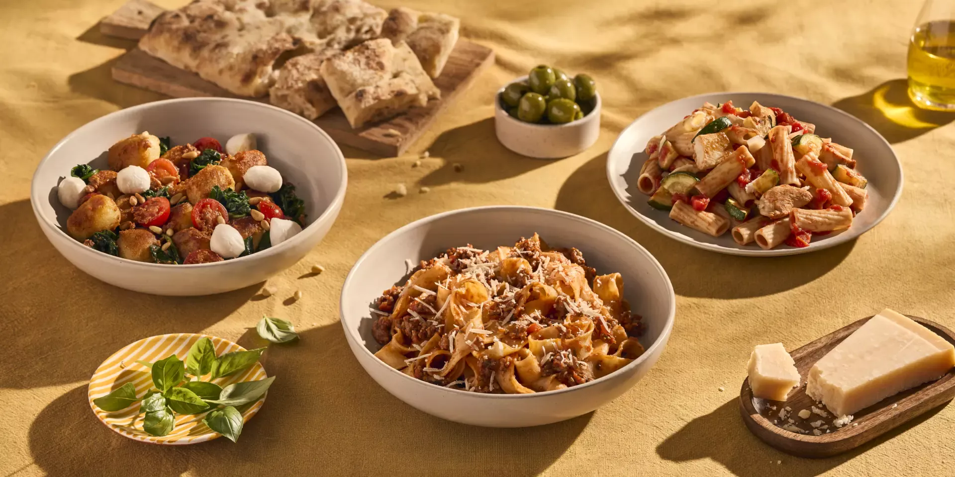 Een gedekte tafel met drie bordjes pasta. Bordje 1 is een heerlijke pappardelle met snelle ragù, het tweede bordje is gevulde gnocchi krokant gebakken met Pesto Rosso, spinazie, tomaatjes en mozzarella. Het laatste gerecht is Rigatoni Half Volkoren met een lekker saus van Sugocasa en veel groenten.